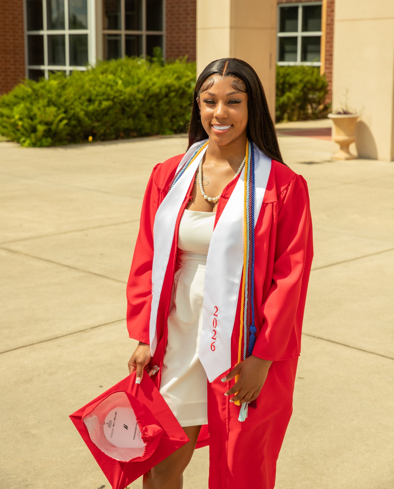 Graduate wearing a red gown and honor cords outdoors